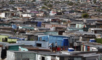 Residents walk through shacks in Cape Town's crime-ridden Khayelitsha township in this picture taken July 9, 2012. At least 11 people have died at the hands of vigilantes in the township since January as angry residents, tired of poor policing, take the law into their own hands. Picture taken July 9, 2012. To match Feature SAFRICA-CRIME/ REUTERS/Mike Hutchings (SOUTH AFRICA - Tags: CRIME LAW) - RTR34VDA